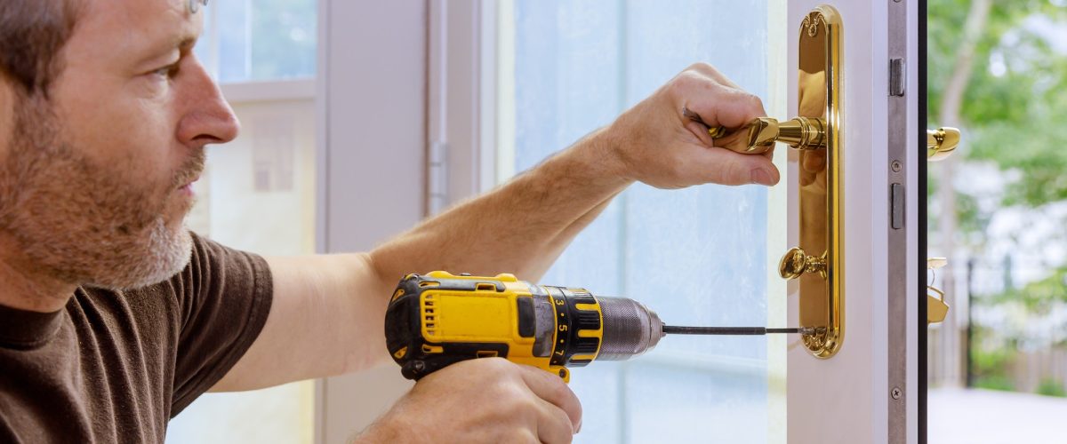 Closeup of a professional locksmith installing or repairing a new deadbolt lock